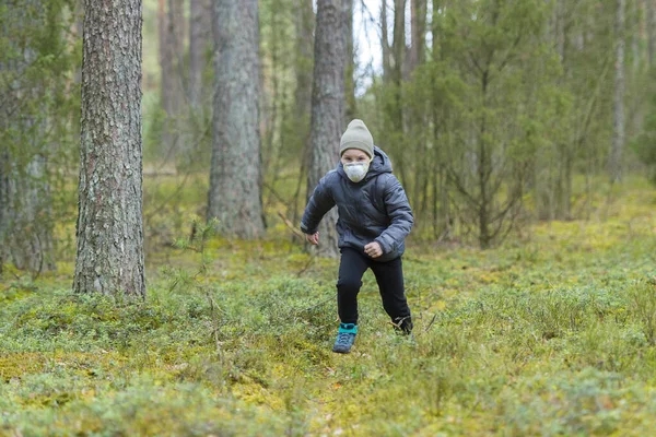 Little boy with a mask run in the forest. Corona virus quarantine