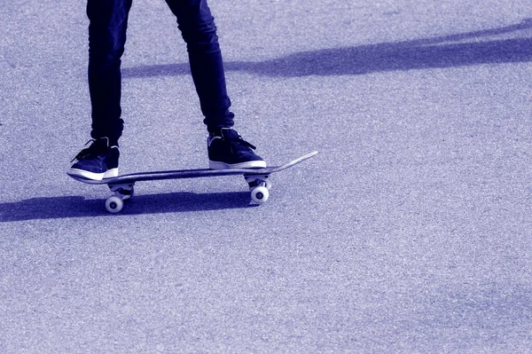 young boy wear jeans and black shoes is skateboarding on the street. Phantom color trend