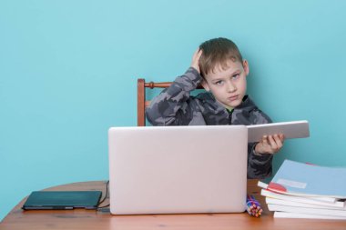 Okul çocuğu evde ödevlerini yaparken dizüstü bilgisayar kullanıyor. Evde eğitim. Evden okula.