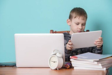 Okul çocuğu evde ödevlerini yaparken dizüstü bilgisayar kullanıyor. Evde eğitim. Evden okula. 