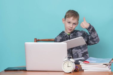 Okul çocuğu evde ödevlerini yaparken dizüstü bilgisayar kullanıyor. Evde eğitim. Evden okula. 