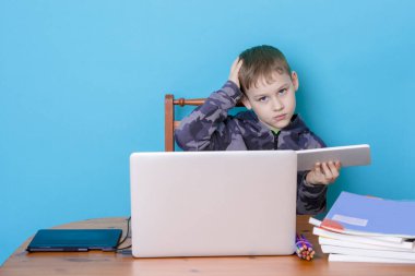 Okul çocuğu evde ödevlerini yaparken dizüstü bilgisayar kullanıyor. Evde eğitim. Evden okula.