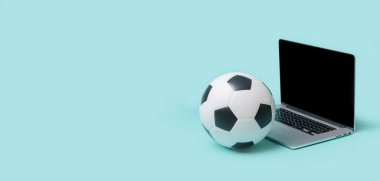 Mavi arka planda futbol topu olan dizüstü bilgisayar. Çevrimiçi çalıştırma kavramı