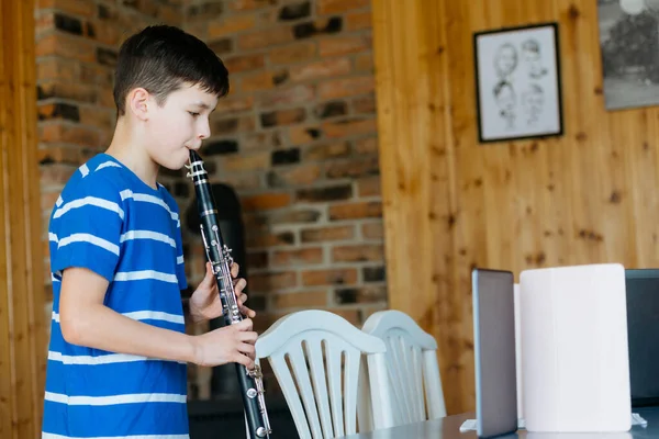 Boy with a clarinet plays music. Online music lesson concept