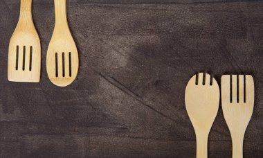 Gri arka planda çeşitli ahşap mutfak aletlerinin üst görüntüsü. Sıfır atık