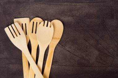 Gri arka planda çeşitli ahşap mutfak aletlerinin üst görüntüsü. Sıfır atık