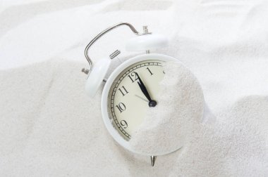 Alarm clock in sand on beach. Vacation time concept clipart