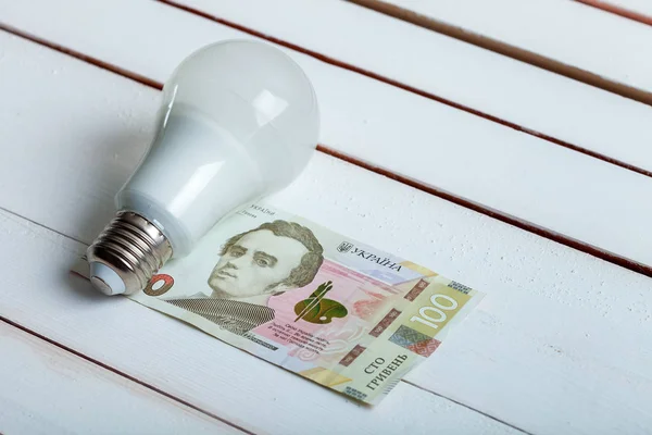 LED žárovka s penězi na stole. — Stock fotografie