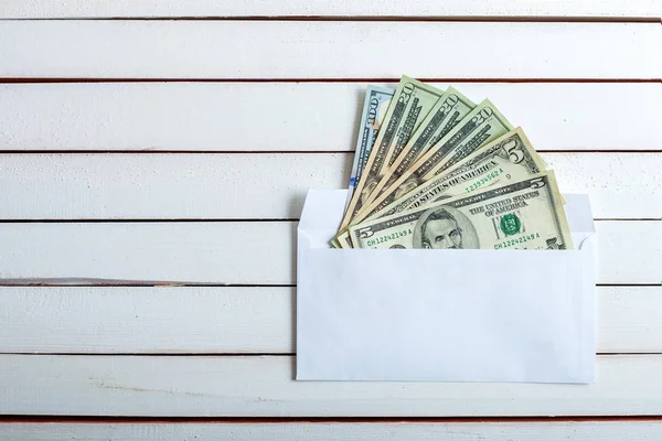 Dinheiro em um envelope na mesa de madeira branca . — Fotografia de Stock