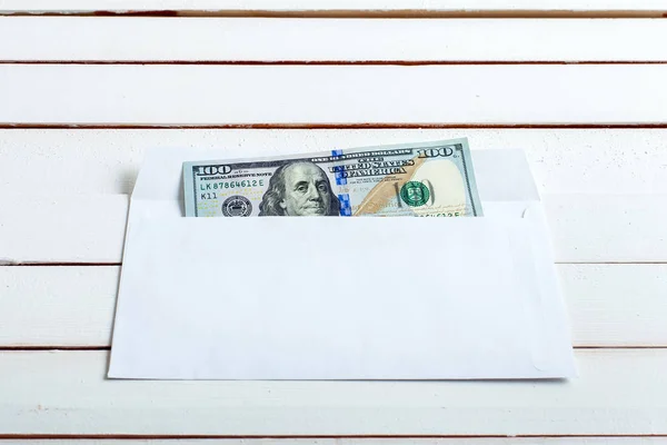 Cash in an envelope on white wooden table.