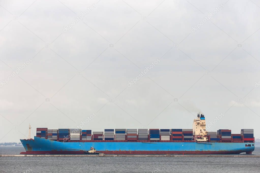 Cargo ship  with  tugboat maneuver to the port.