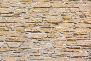 Binanın ön cephesindeki taş duvarın dokusu sarı doğal taş katmanlarıyla süslenmiş..