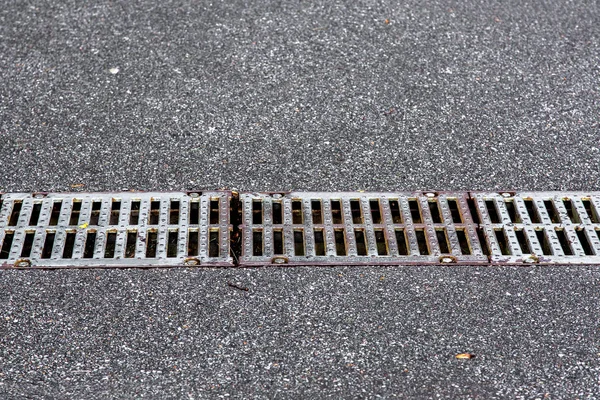 iron grid drainage system on an asphalt road, closeup.