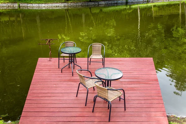 outdoor river cafe with tables and chairs on a wooden red pier on the pond, empty chairs nobody.