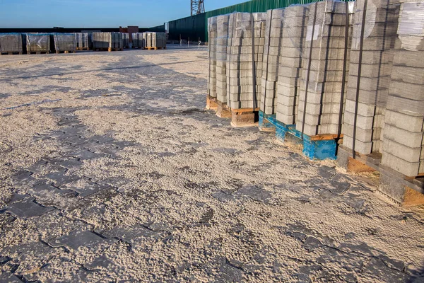 Güneşli bir günde, kaldırımdaki palete katlanmış ve paketlenmiş yeni kaldırım taşları..