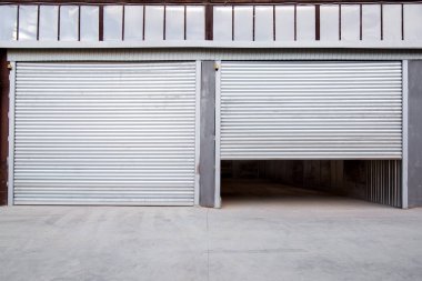 Gri beton verandalı endüstriyel bir binanın gri demir kepengi..