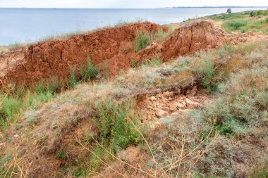 Sahildeki toprak yığını, toprağın kil katmanları yamaçtan aşağı kayıyor..