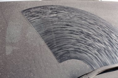 Kirli bir arabanın arka camında toz ve kuru toprak tabakası var. Kirli bir aracın fotokopi alanı var..