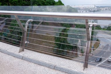 construction details of a glass bridge with steel fixtures with a railing and a granite curb at the edge of a pedestrian glass bridge, city on background nobody. clipart