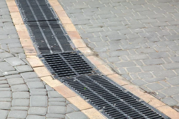 人行横道上用石砖建成的黑色格栅排水系统 — 图库照片