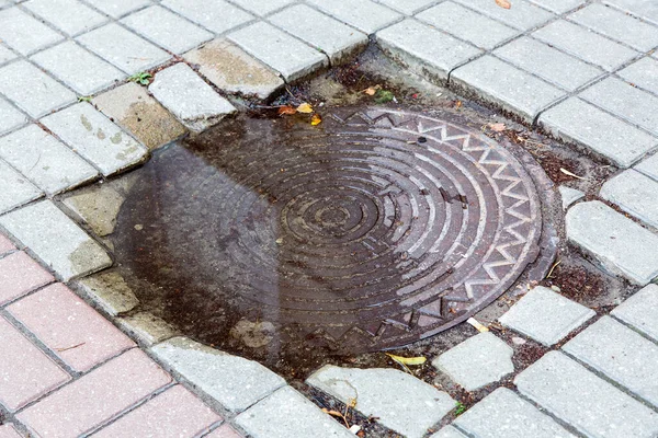 Ijzer Ronde Putdeksel Een Plas Water Een Voetgangers Stoep Gemaakt — Stockfoto