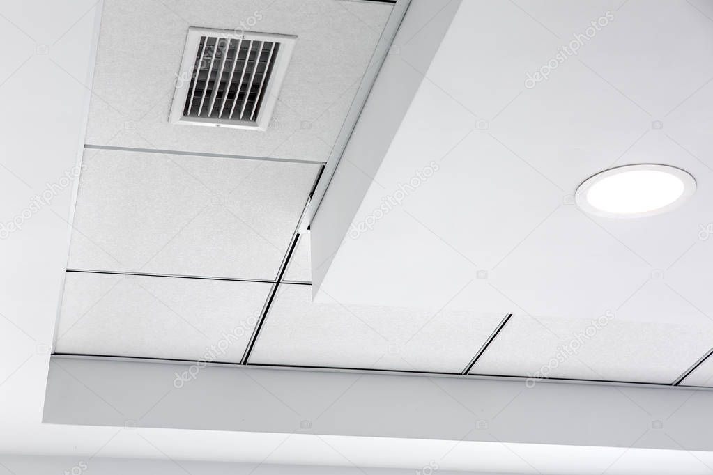 multi-level ceiling with three-dimensional protrusions and a suspended tiled ceiling with a built-in round led light and grille ventilation system, close up details.