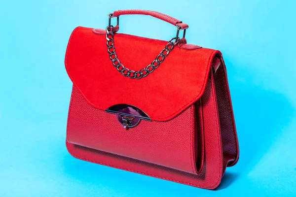 women's handbag in red leather and suede, side view 3/4 object on a blue background.