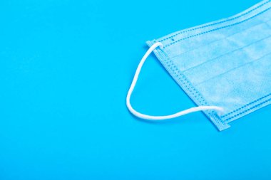 Koruyucu tıbbi maske, sağlık hizmetleri objesi ve kopya alanı olan mavi bir arka planda virüse karşı koruma.