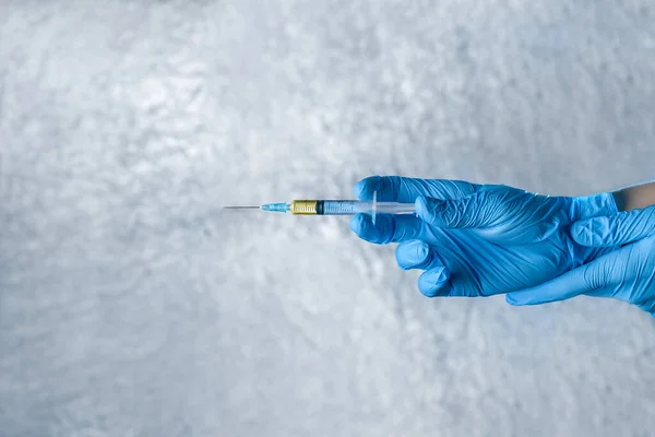 hands in medical gloves holding a syringe with a vaccine as a gun for self-defense against the virus, medical background concept with copy space.