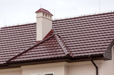 Seramik bir fayansın kahverengi çatısı borusu fırtına drenaj sistemi ve havalandırma borusu olan bir evin mimari yapısının detaylarını kapatın..