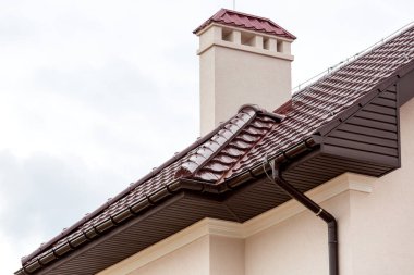Seramik bir fayansın kahverengi çatısı borusu fırtına drenaj sistemi ve havalandırma borusu olan bir evin mimari yapısının detaylarını kapatın..