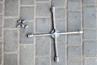 Çapraz anahtar, tekerlek fındıklarını gevşetmek için farklı boyutlarda kafa, araba servisi için bir araç yerde yatıyor..