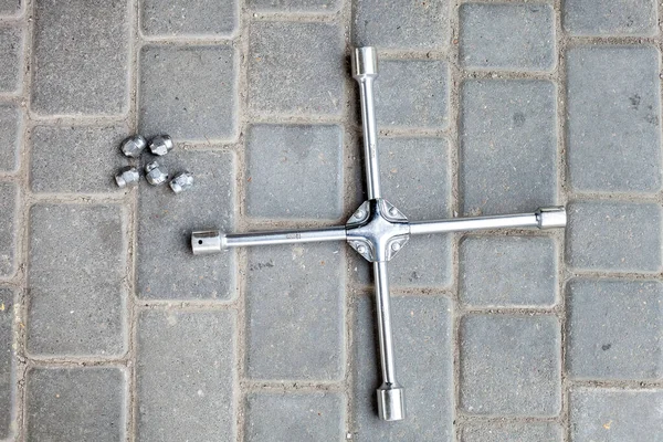 a cross wrench with different sizes of heads for loosening wheel nuts, a tool for car service lies on the ground a top view.