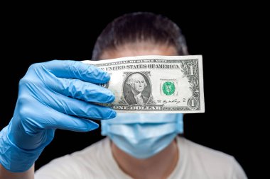 Tıbbi eldivenli 1 dolarlık banknotta hasta maskeli bir adam var. Coronavirus covid-19 'un tedavi ve sigorta masrafları üzerine bir konsept..
