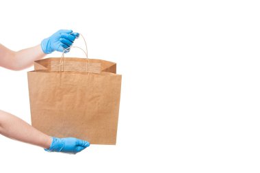 Elleri steril bir kuryenin eldiveni içinde. Ürünlerin güvenli bir şekilde, çevre dostu bir pakette teslim edilmesi için. Etiketsiz bir paket görünüyor..