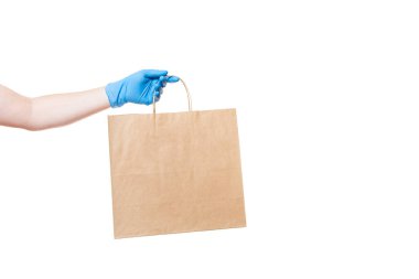 Kahverengi bir kağıt eko dostane paket steril eldivenli bir teslimatçının elini tutuyor. Beyaz bir arka planda, fotokopi aletiyle izole edilmiş. Virüs salgını sırasında güvenli bir şekilde teslim ediliyor..