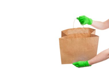 Bir kuryenin temiz yeşil eldivenlerini, çevre dostu pakette güvenli bir şekilde taşıması için, beyaz arka planda izole edilmiş ve fotokopi alanı olan etiketsiz bir paket gösteriyor..