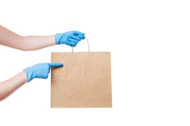 Bir kuryenin steril eldiveni içinde yiyecek teslimatı için çevre dostu bir paketteki bir kuryenin elleri bir logo için boş bir yeri işaret ediyor, beyaz arka planda kopyalama alanı ile izole edilmiş bir şekilde taklit ediyor..