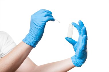 Doktor, virüs testi için ağız boşluğundan örnek almak üzere şişeye pamuk çubuğu vermek üzere mavi steril eldiven verdi. Beyaz arka planda izole edilmiş tıbbi temayı taklit etti..