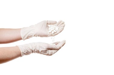 Steril beyaz eldivenler beyaz arka planda izole edilmiş beyaz bir uyuşturucu bağımlılığı konsepti olan tabletleri elden ele döküyor..