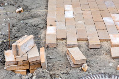 Dikdörtgen taş kiremitlerden yeni bir kaldırım döşenmiş. Katın gerilmiş iplikçiklerinin izlerine göre, taş yolun onarımına yakın plan..