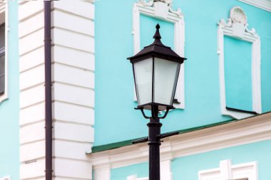 Binanın ön cephesinde, bir sütunun üzerinde cam gölge ile demir siyah retro fener, yakın çekim.