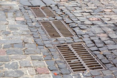 kaldırım taşlarıyla döşenmiş kaldırım kapağının demir ızgarası ile döşenmiş yol, yakın çekim.