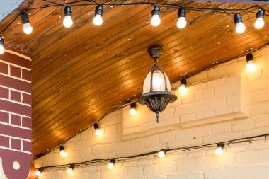 Tavanda asılı demir retro fener bir binanın ön cephesinde bir ampul ile bir çelenk ile süslenmiş yakın çekim.