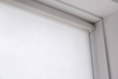Beyaz rulo tekstil jaluzileri bir odanın penceresinde, güneş ışığına karşı korunma objesi kopya alanı ile kapatın.
