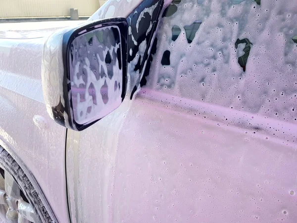 体を洗うための汚れた車の泡 ピンクのワックスフォームのリアビューミラーで運転者のドアを洗うのクローズアップ — ストック写真