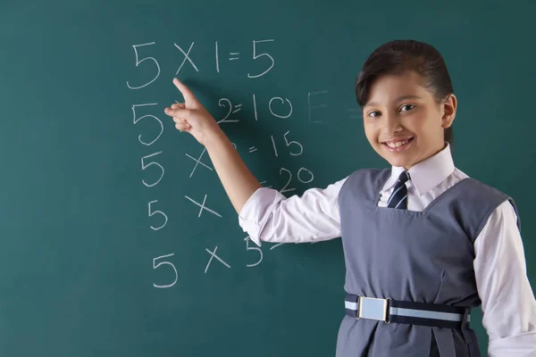 Sonriente chica apuntando a las mesas escritas o — Foto de Stock