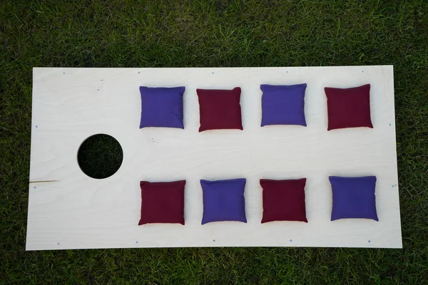 Cornhole Board Flat Lay con bolsas de frijoles en la hierba — Foto de Stock