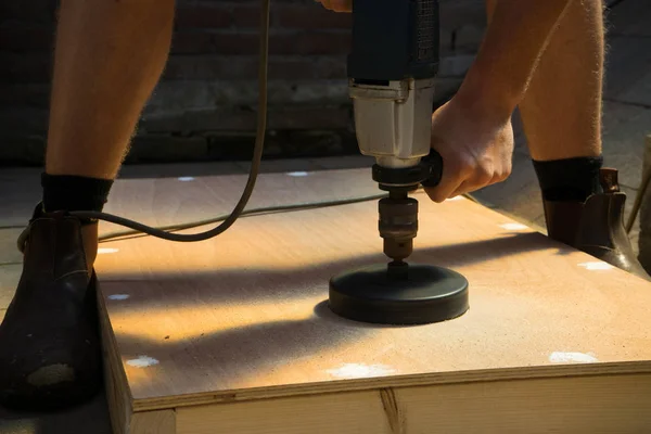 Sawdust from man cutting hole in cornhole board DIY Stock Picture