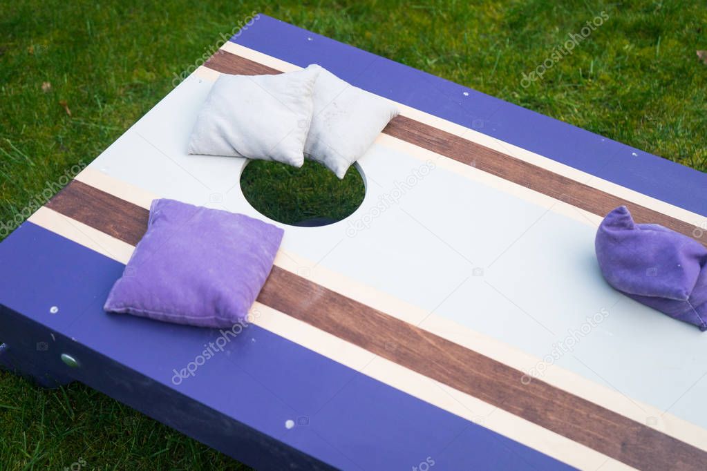 Cornhole beanbag toss wood game board outside on grass